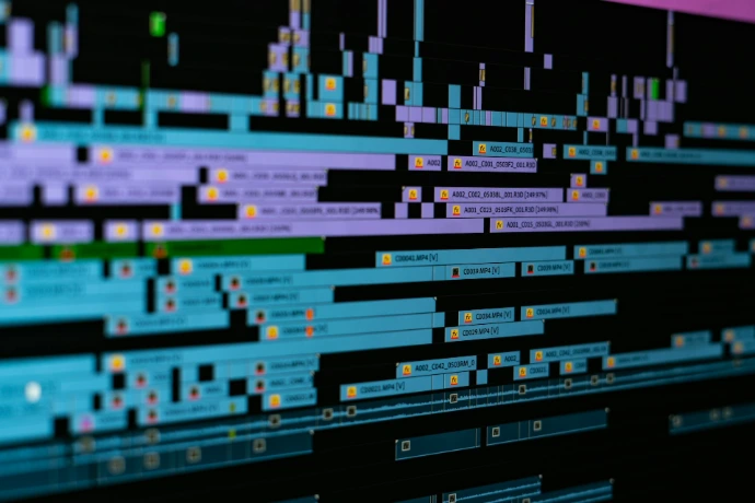 A digital video editing timeline with blue and purple clips on a black background